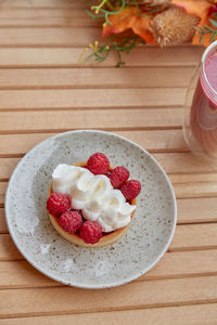 Aesthetic healthy autumn lunch - pink strawberry smoothie and french tart on the wooden table.