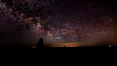 Silhouette person against sky at night