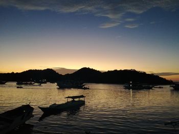 Boats moored on sea against sky during sunset