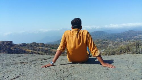 Rear view of boy on landscape against sky