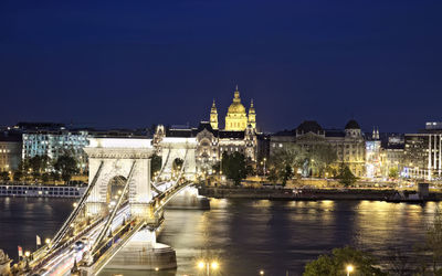 Illuminated bridge over river against sky in city at night