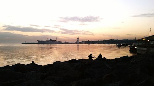 Silhouette people on beach against sky during sunset