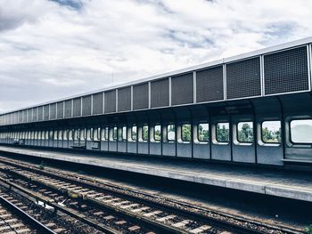 Railroad tracks against cloudy sky