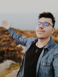 Portrait of young man standing against sky