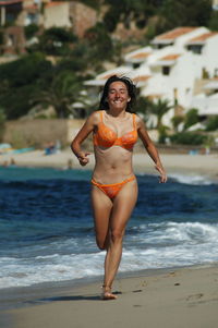 Full length of smiling woman running on beach