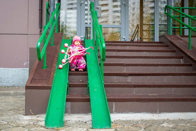 Toddler drags a toy stroller along the ramp of the stairs