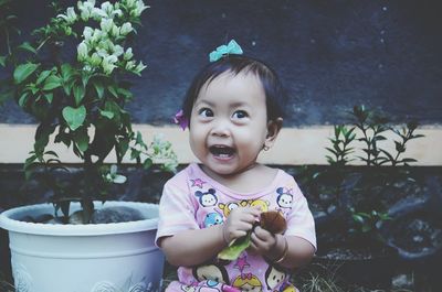 Portrait of cute baby girl in potted plant