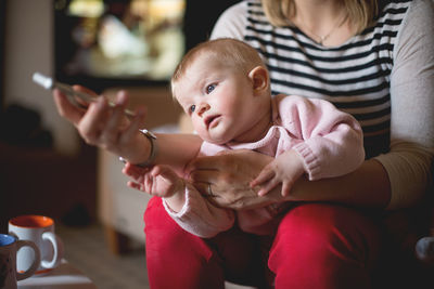 Midsection of mother with daughter at home