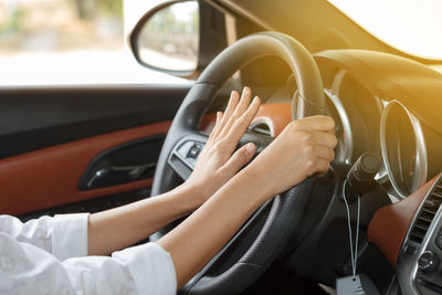 Cropped hands of woman driving car
