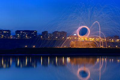 Wire wool spinning by river against sky at night