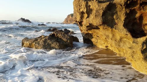 Scenic view of rocks on beach against sky