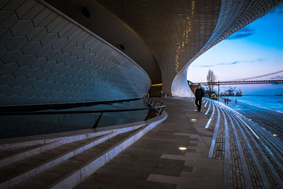 Rear view of people walking on illuminated bridge