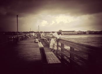 Pier on sea against cloudy sky