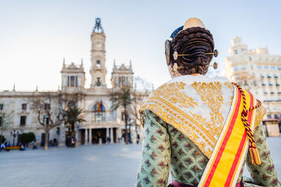 Rear view of man outside temple against buildings in city