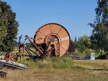 Old rusty wheel on field against sky