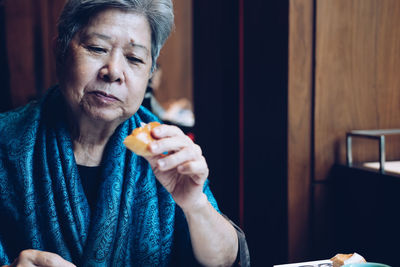 Senior woman eating breakfast at home