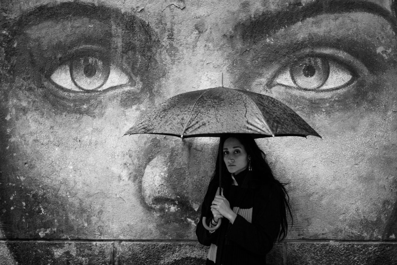 PORTRAIT OF A YOUNG WOMAN STANDING WITH RAIN