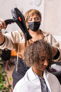 Hairdresser styling customer hair at salon