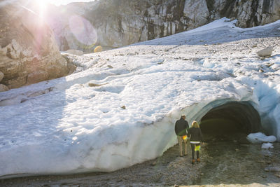 Retired couple enter ice cave during luxury excursion.