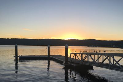 Pier over lake against sky during sunset