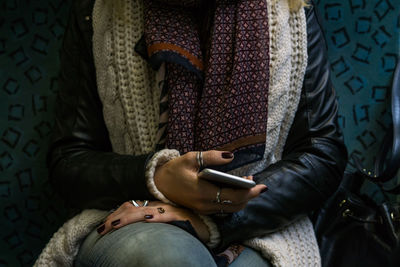 Midsection of woman holding mobile phone in train