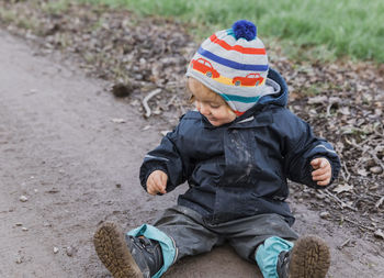 Full length of cute girl sitting on dirt road