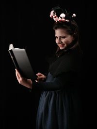 Young woman using smart phone against black background