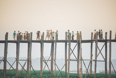 People standing by railing against clear sky