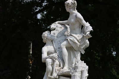 Low angle view of angel statue against trees