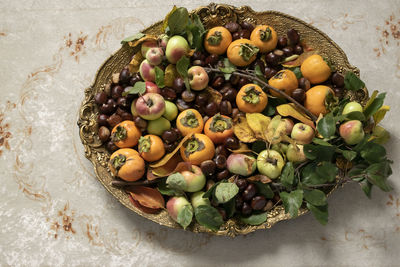 Autumn fruits dish. fresh raw apples, kaki and chestnuts on a golden tray