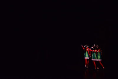 Women wearing costume while standing against black background