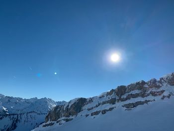 Scenic view of snowcapped mountains against blue sky