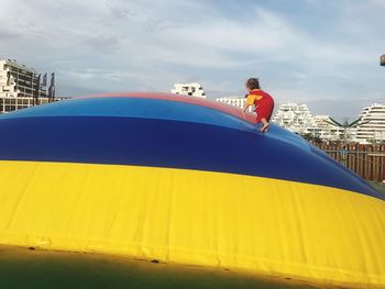 Girl climbing on giant ball against sky