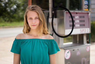 Portrait of young woman standing at gas station