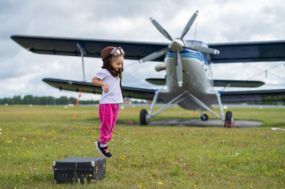 Full length of girl jumping in front of air plane