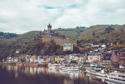 Buildings by river against sky in city
