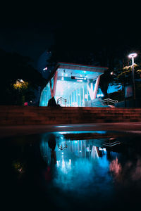View of swimming pool by building at night