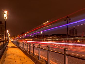 Light trails on bridge against sky at night