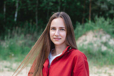 Candid portrait of a young caucasian woman in red clothes playing with her hair, posing