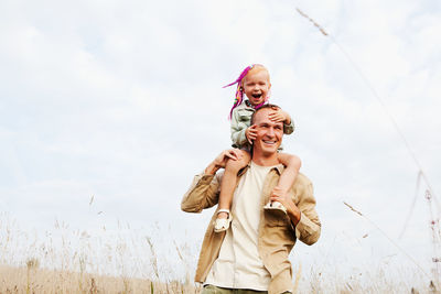 Happy people enjoy their life. beautiful dad holds smiling daughter on his shoulders in nature