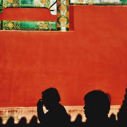 Silhouette people standing against red wall