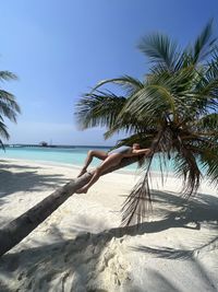 Low angle view of woman on palm tree against clear sky