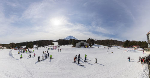 People skiing on snowy field against sky