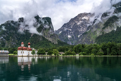 Scenic view of church by lake against mountains