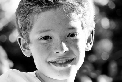 Close-up portrait of smiling boy with freckles on face