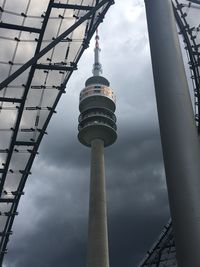 Low angle view of communications tower against cloudy sky