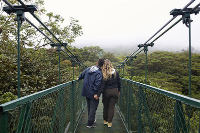 Rear view of woman standing on footbridge