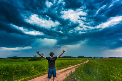 Rear view of man standing on land against sky