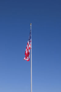 Low angle view of flag flags against clear blue sky