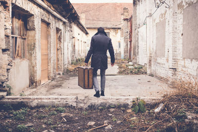 Rear view of man walking on alley amidst buildings